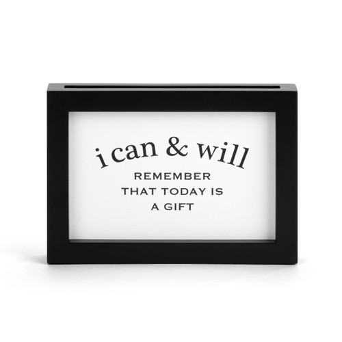 Close up view of the black rectangular frame with an opening in the top to insert different "i can & will" encouraging statement cards.