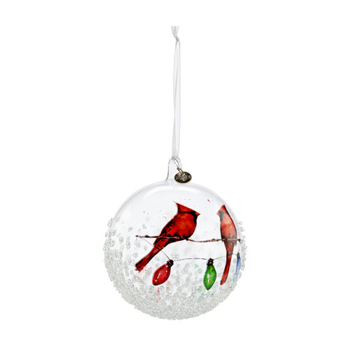 A clear glass ball ornament with an image of two cardinals sitting on a holiday string of lights, displayed angled to the right.