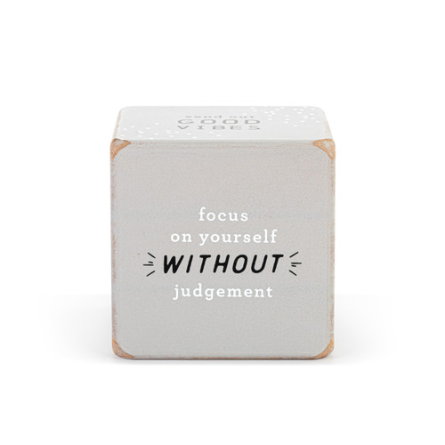 A large gray wood dice with an inspirational saying on each side in white and black print.