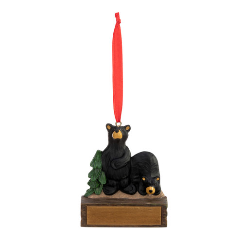 An ornament of two black bears on a rock next to an evergreen tree, hanging from a red ribbon. There is a spot in front for customization.