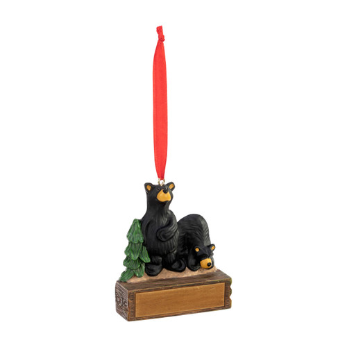 An ornament of two black bears on a rock next to an evergreen tree, hanging from a red ribbon. There is a spot in front for customization, displayed angled to the right.