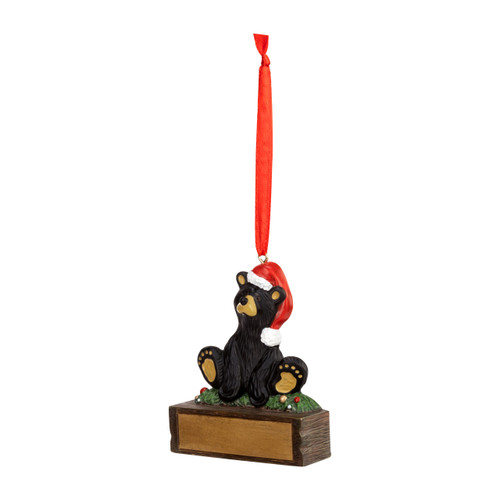 A hanging ornament that has a black bear in a Santa hat on a rectangular base that can be personalized, angled to the left.