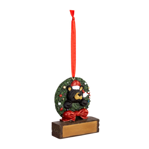 A hanging ornament with a black bear wearing a Santa hat poking through a green holiday wreath on a rectangular base that can be personalized, displayed angled to the right.
