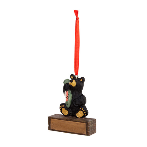 A hanging ornament with a black bear sitting and holding a fish on a rectangular base that can be personalized, displayed angled to the left.