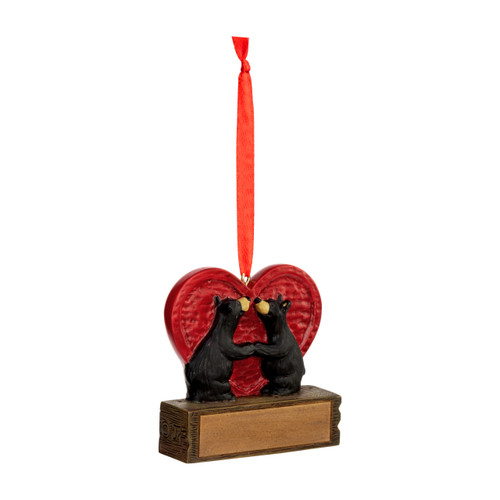 A hanging ornament of two black bears looking at each other in front of a large red heart on a rectangular base that can be personalized, displayed angled to the right.