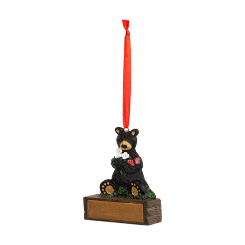A hanging ornament of a black bear holding white flowers with a red butterfly on its arm sitting on a rectangular base that can be personalized, displayed angled to the left.