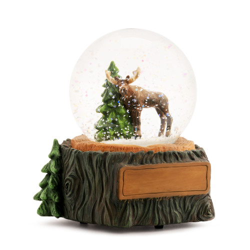 A glass snow globe with a moose and pine tree inside. The base is sculpted like a tree trunk and has a rectangle on the front for personalization, displayed angled to the right.