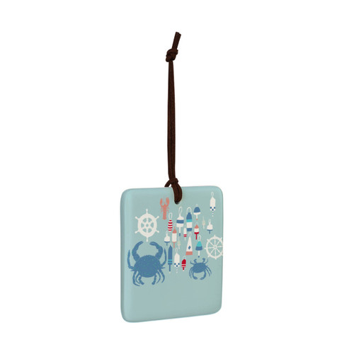 A square sea blue hanging tile magnet ornament with an illustration of buoys, crabs and ship wheels, displayed angled to the right.