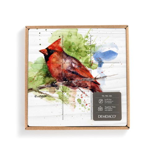 A square white wood board for tic tac toe with a watercolor image of a red cardinal, displayed in a packaging box.