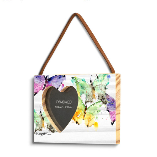 A rectangular wood hanging frame with a heart shaped 2 inch photo opening next to a watercolor image of colorful butterflies, displayed angled to the left.
