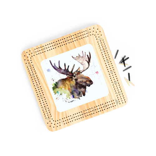 A light wood cribbage board with a watercolor image of a moose in the middle, displayed angled to the right with the playing pieces to the side.