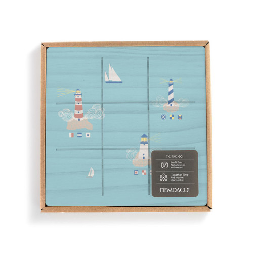 A square blue wood board for tic tac toe with an illustration of lighthouses and sailboats, displayed in a packaging box.