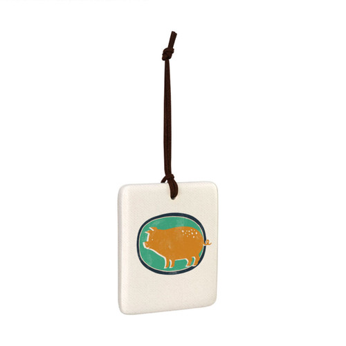 A square white tile hanging magnet ornament with a gold pig on a green background, displayed angled to the right.