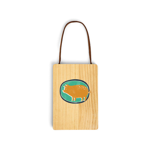 A wood hanging gift card ornament with an illustration of a gold pig on a green background. The back has a holder for a gift card.