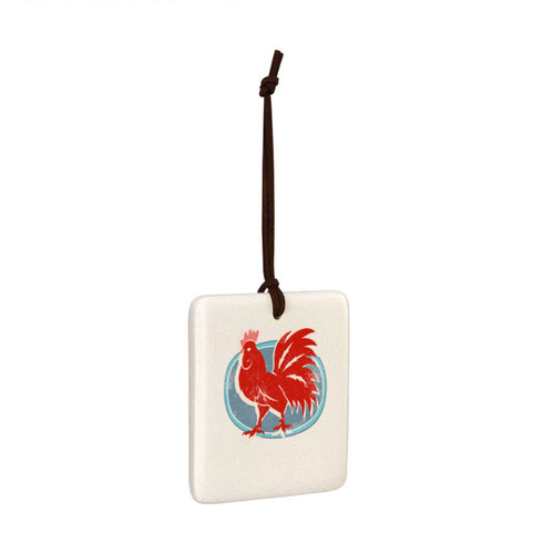 A square white tile hanging magnet ornament with a red rooster on a blue background, displayed angled to the right.