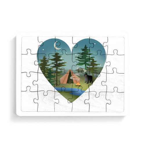 A 24 piece postcard puzzle with a heart shaped graphic image of a wooded campsite with a curious bear.