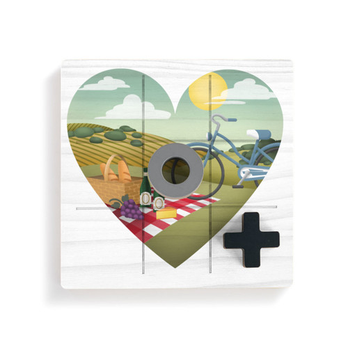 A square white wood board for tic tac toe with heart shaped graphic artwork depicting a wine and cheese picnic on a hillside, displayed with a gray O and black X on top.