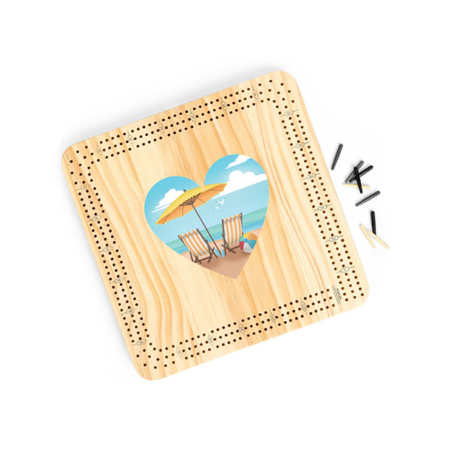 A light wood cribbage board game with heart shaped graphic artwork of two beach chairs and an umbrella in the middle, displayed angled to the right with the playing pieces off and to the right.