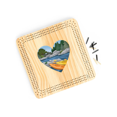 A light wood cribbage board game with heart shaped graphic artwork of kayaks at a rivers edge in the middle, displayed angled to the right with the playing pieces off and to the right.