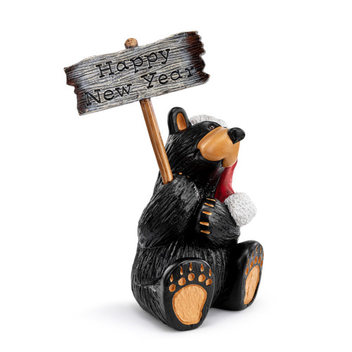 A grand figurine of a sitting black bear wearing a Santa hat and holding a sign that says "Happy Holidays". The sign is reversible and removable, displayed angled to the right with the reverse sign up that says "Happy New Year".