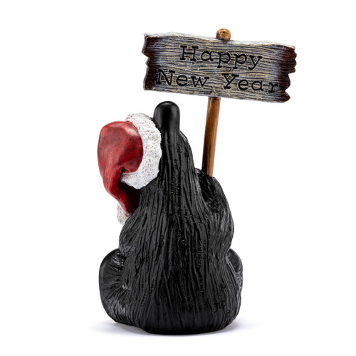 Back view of a grand figurine of a sitting black bear wearing a Santa hat and holding a sign that says "Happy Holidays". The sign is reversible and removable.