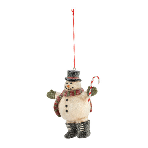 A hanging ornament of a snowman wearing boots, top hat, green mittens and a scarf while holding a candy cane, displayed angled to the left.