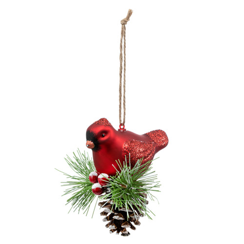A red cardinal bird ornament with the bird sitting on a snowy pinecone and evergreen branch, displayed angled to the left.