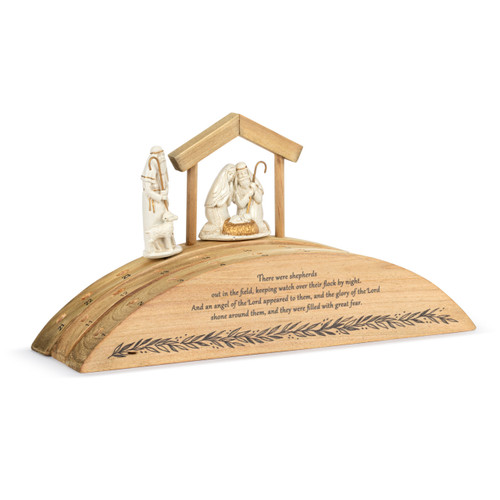 A wood Advent countdown calendar with a Bible verse on the front. There is a shepherd figure and holy family figure, displayed angled to the right.