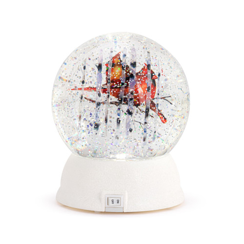 Back view showing the on/off switch on a lit snow globe with a white base and a watercolor image of a pair of cardinals inside.