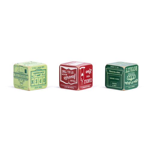 A set of three red and green painted wood dice with instructions on them for a holiday gift exchange game, displayed with different sides showing.