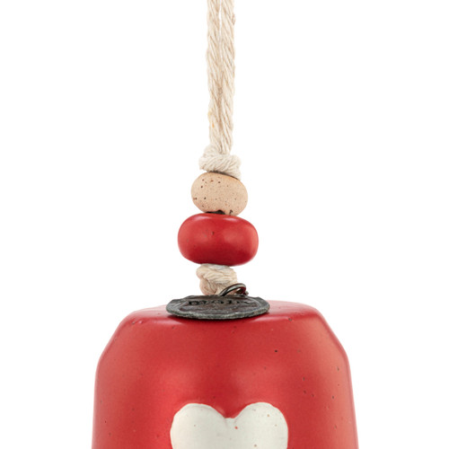 Detail view of the beads on a mini red bell with a white heart on the front. There are beads and a metal token at the top of the bell.