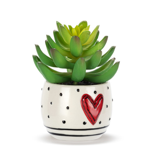 A mini white ceramic container with black dots, stripes and a raised red heart on the front. The container has an artificial succulent, displayed angled to the right.