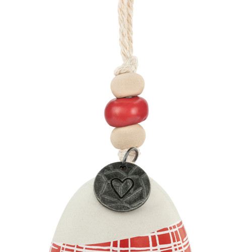 Detail view of the beads on a mini white and red bell with a plaid pattern. There are beads and a metal token at the top of the bell.
