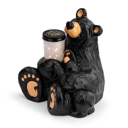 An adult black bear sitting holding a jar of fireflies in his right arm and a curious small bear in his left arm, displayed angled to the left.