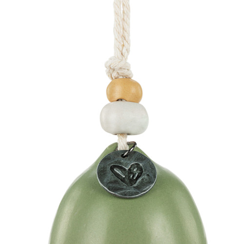 Detail view of the beads on a mini green bell with a cream heart and the word "pause". There are beads and a metal token at the top of the bell.