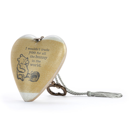 Heart shaped sculpture with a silver tassel and metal key attached. The heart has the image of Pooh eating honey on a brown background and says "I wouldn't trade you for all the hunny in the world", displayed angled to the left.