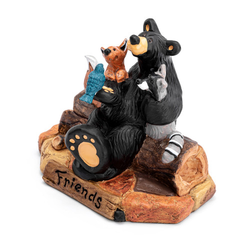 A figurine of a black bear sitting on a log with his forest friends including a fox, racoon and bird. The base says "Friends", displayed angled to the left.
