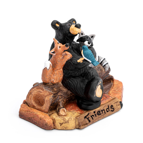 A figurine of a black bear sitting on a log with his forest friends including a fox, racoon and bird. The base says "Friends", displayed angled to the right.