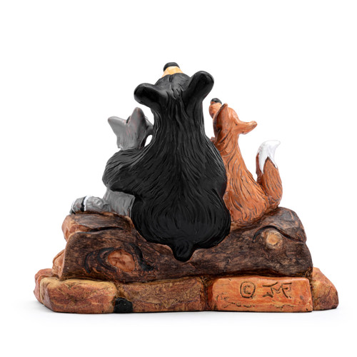 Back view of a figurine of a black bear sitting on a log with his forest friends including a fox, racoon and bird. The base says "Friends".