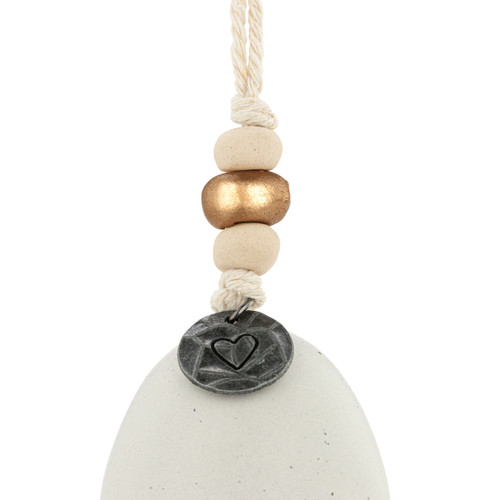Detail view of the beads on a mini cream and gold bell with the word "grateful" on the front. There are beads and a metal token at the top of the bell.