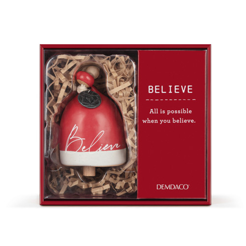 A mini red and white bell with the word "Believe" on the front. There are beads and a metal token at the top of the bell, displayed in a red packaging box.