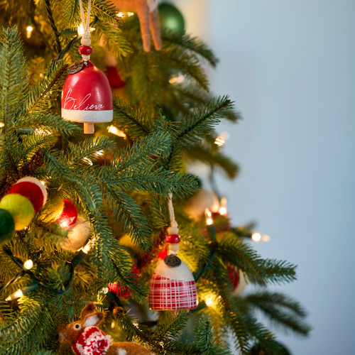 Two different mini bell ornaments in red and white displayed on a decorated green Christmas tree.