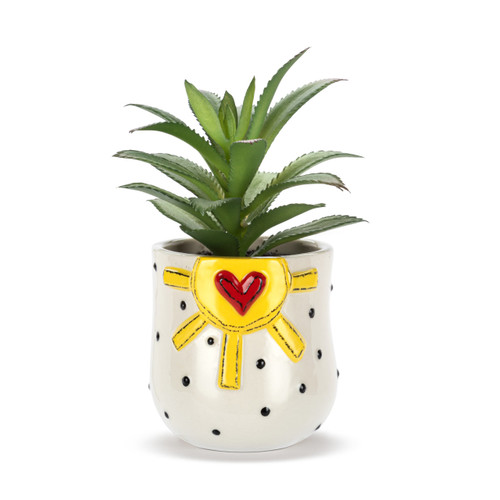 A mini white ceramic container with black dots and a raised yellow sun and red heart. The container has an artificial succulent.