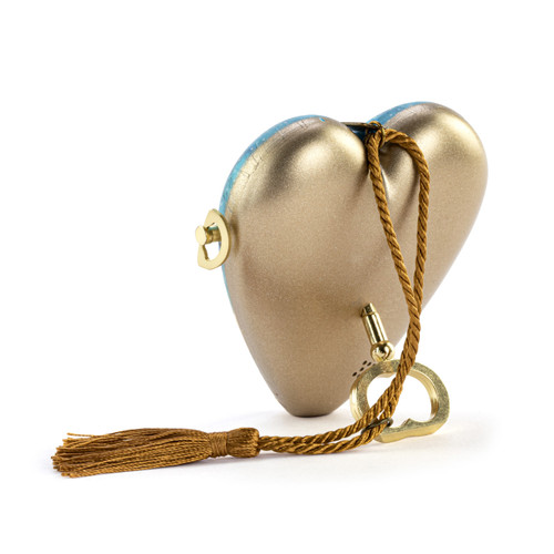 Back view of the heart propped on the key for a blue heart shaped musical sculpture with an image of the holy family. The heart has a gold tassel and gold key attached.