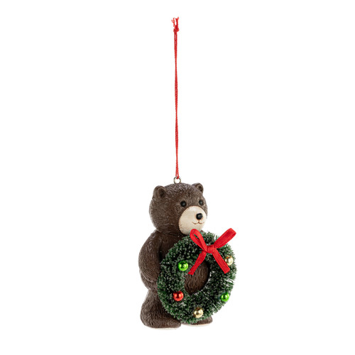 A small brown teddy bear ornament holding a green decorated wreath, displayed angled to the right.