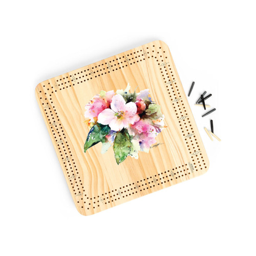 A light wood cribbage board game with the watercolor image of an apple blossom in the middle, displayed angled to the right with the playing pieces off and to the right.