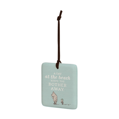 A square light blue hanging tile magnet ornament that says "A Day at the beach Keeps the Bother Away" with an image of Pooh and Piglet, displayed angled to the left.