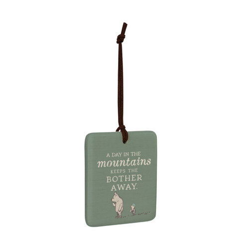 A square green hanging tile magnet ornament that says "A Day in the mountains Keeps the Bother Away" with an image of Pooh and Piglet, displayed angled to the right.