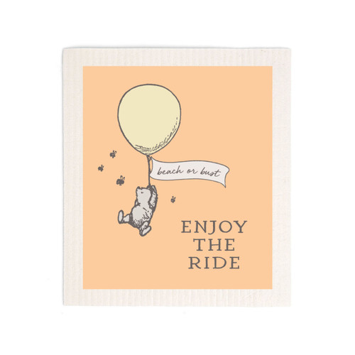 An orange biodegradable dish cloth that says "Enjoy the Ride" with Pooh hanging from a floating balloon that says "beach or bust".