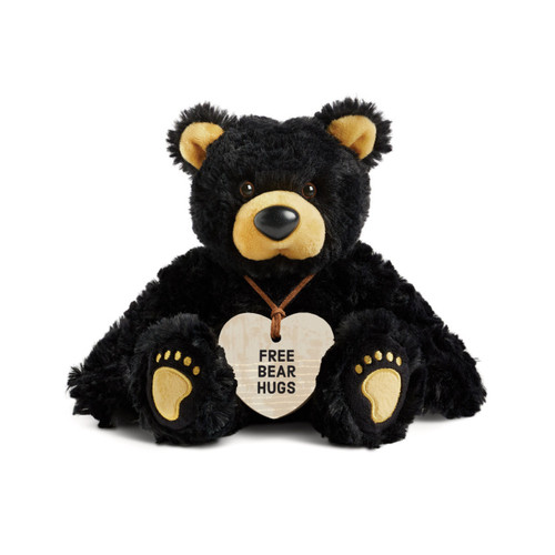 A black plush bear with brown ears, nose and paws. The bear is wearing a heart shaped wood ornament around its neck that says "Free Bear Hugs".